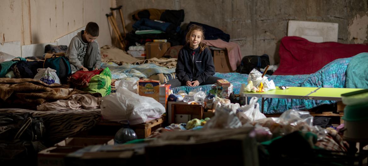 Des enfants sont assis sur un canapé de fortune dans un parking souterrain qui sert d'abri anti-bombes à Kharkiv, dans le nord-est de l'Ukraine.